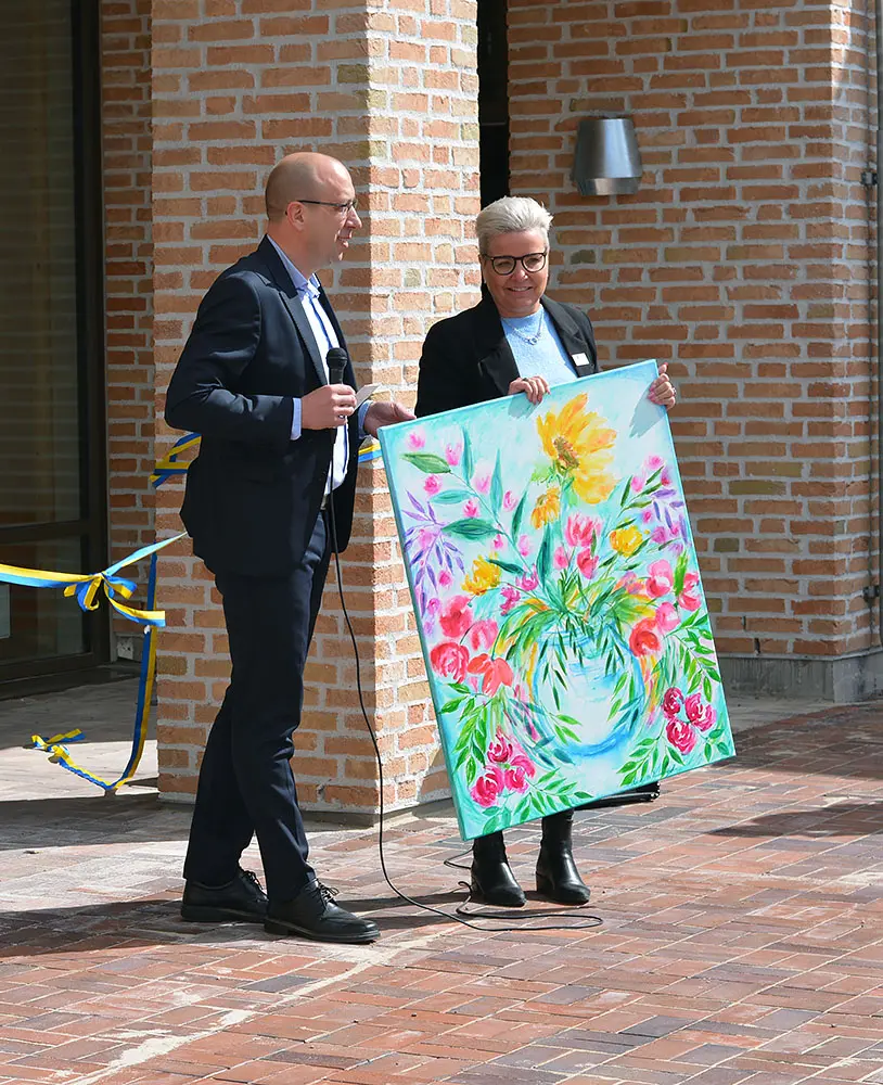 Magnus Andersson ler mot publiken och Malin Carlos står med en färgglad målning med blomstermotiv.